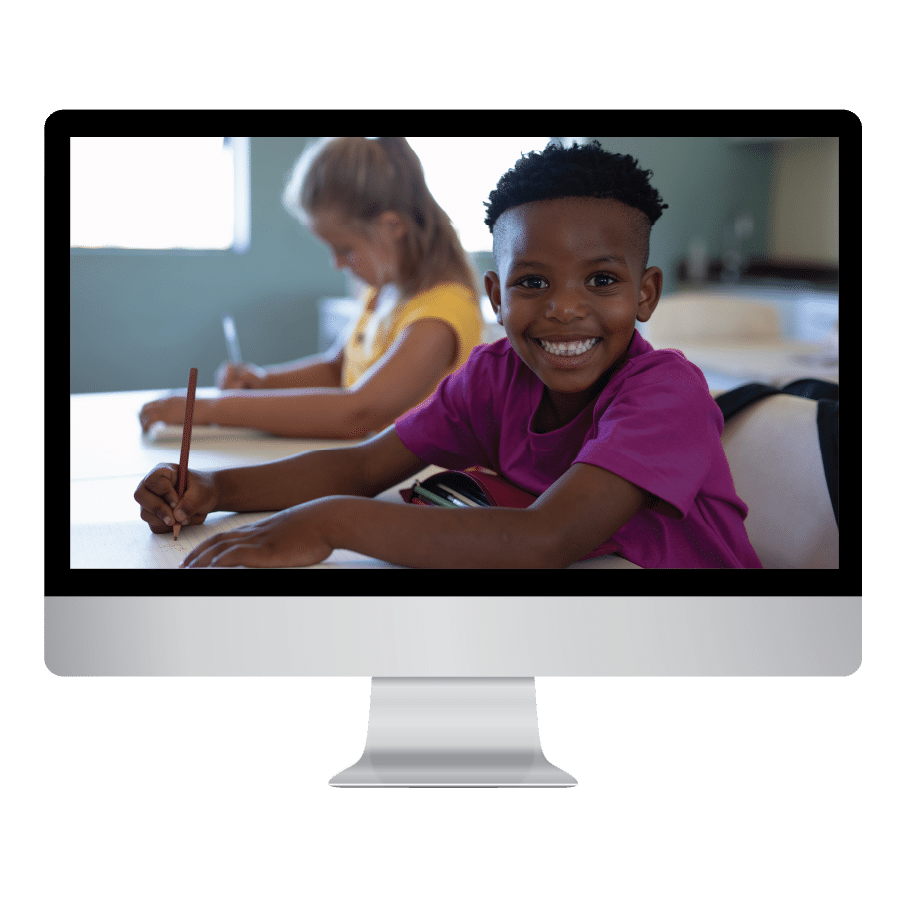 mac screen displaying a boy with big smile writing in classroom