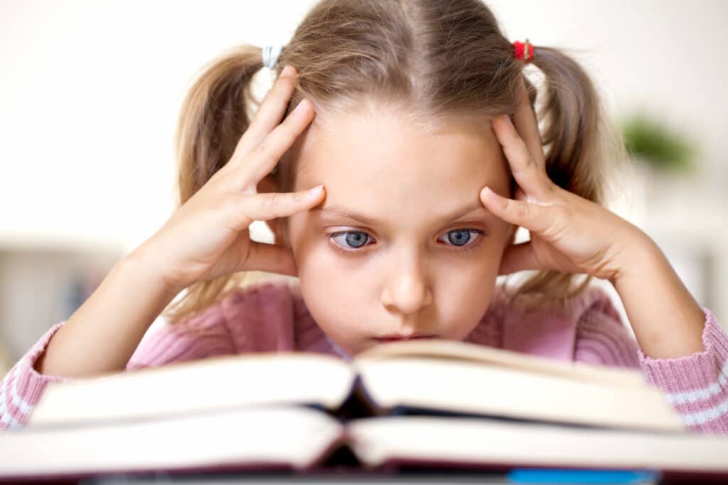 Girl intently staring at book struggling to read