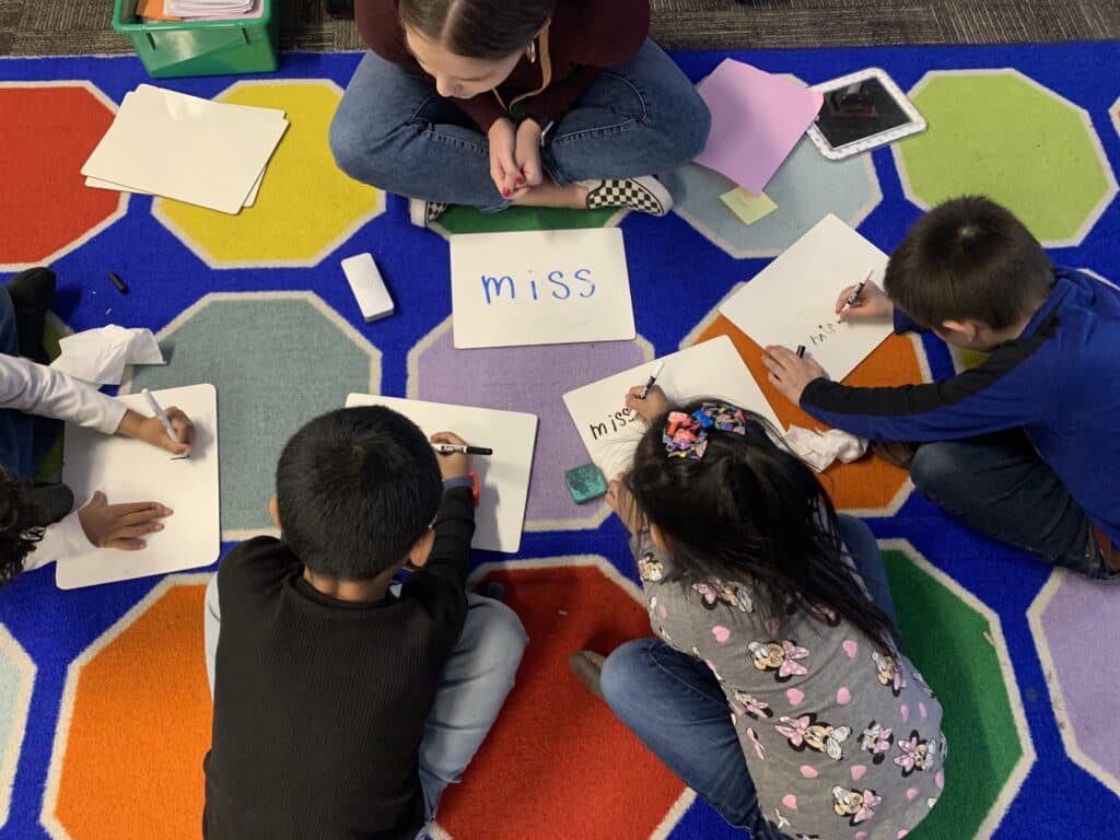 Aerial view of small group and teacher on floor with dry erase boards