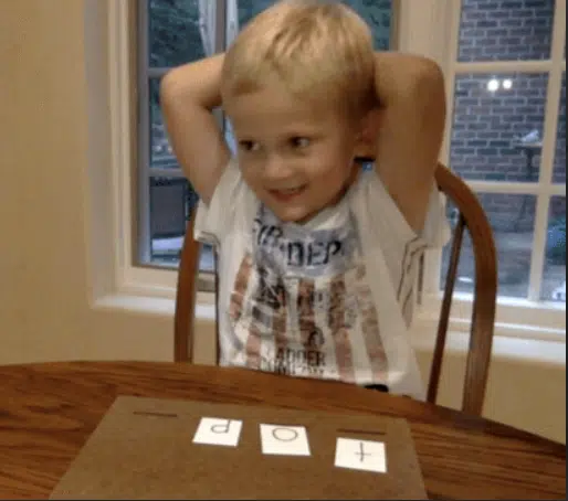 Smiling boy at a table playing Build It