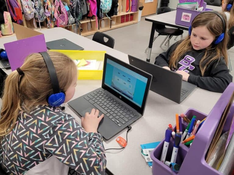 Student facing computer with headphones on playing literacy game