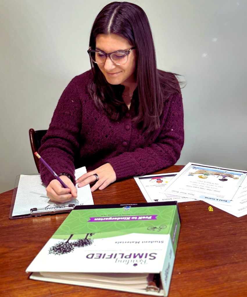 Teacher with K binder writing a lesson plan